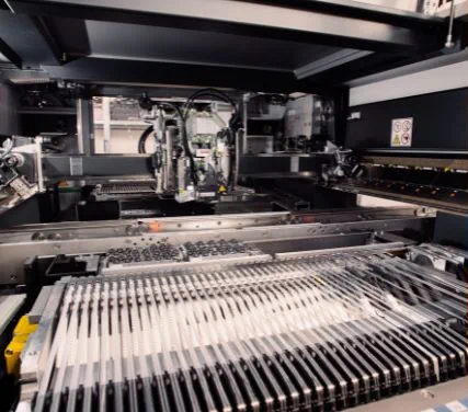 Pick-and-place machine populating circuit boards, with component feeder rails in the foreground